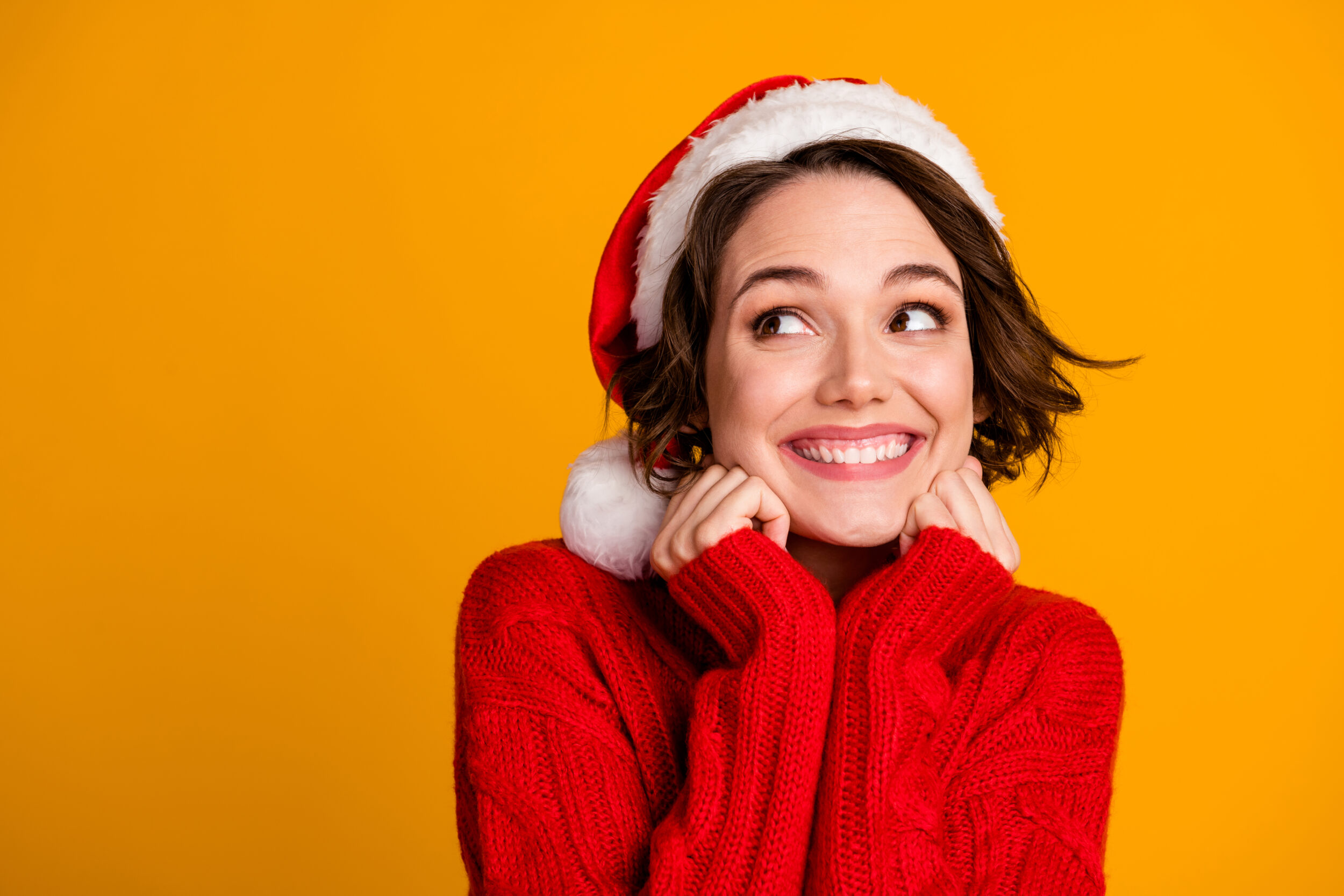 Pretty young woman in Santa hat has fresh complexion before holiday parties